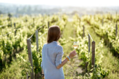 Young,Woman,With,Wine,Glass,Standing,On,The,Beautiful,Vineyard